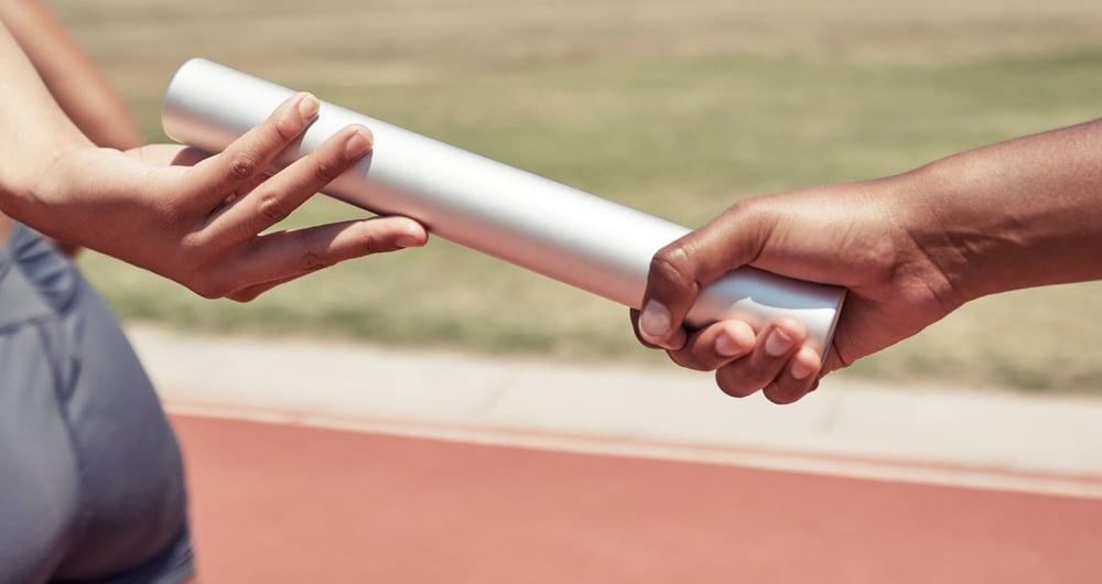 Hands passing baton in relay race